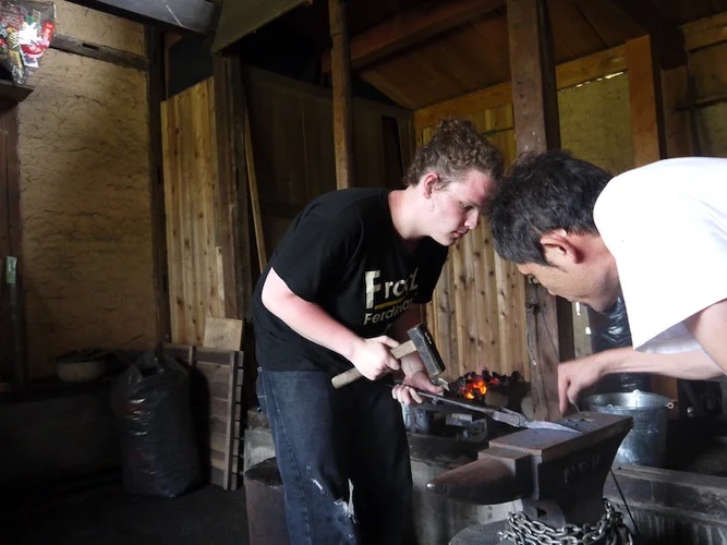 Turistas haciendo un cuchillo con ayuda de los artesanos en Gifu.