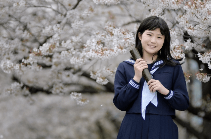 estudiante japonesa portando su diploma de graduación.