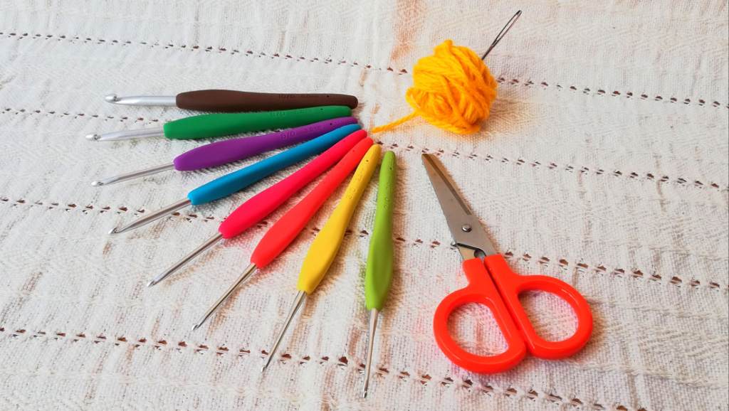 Herramientas como tijeras, hilo de estambre y aguja para tejer amigurumis.