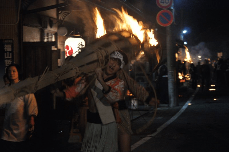 Participantes gritando mientras caminan con la antorcha sobre sus hombros.
