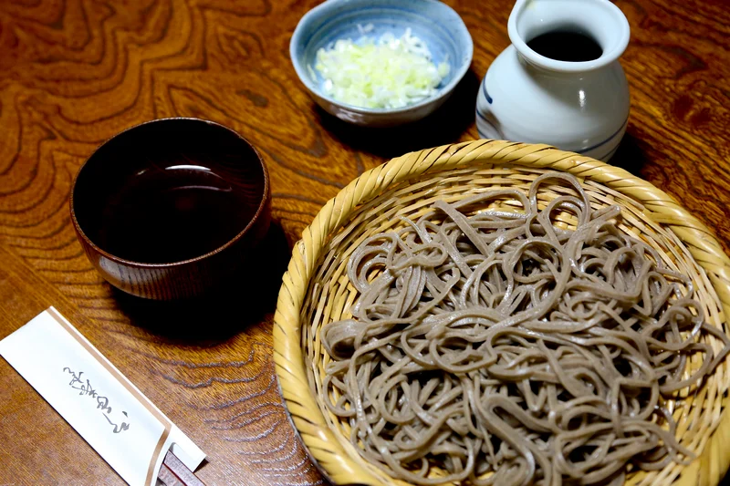 Un plato típico de mori soba con clado tsuyu y condimentos al lado.